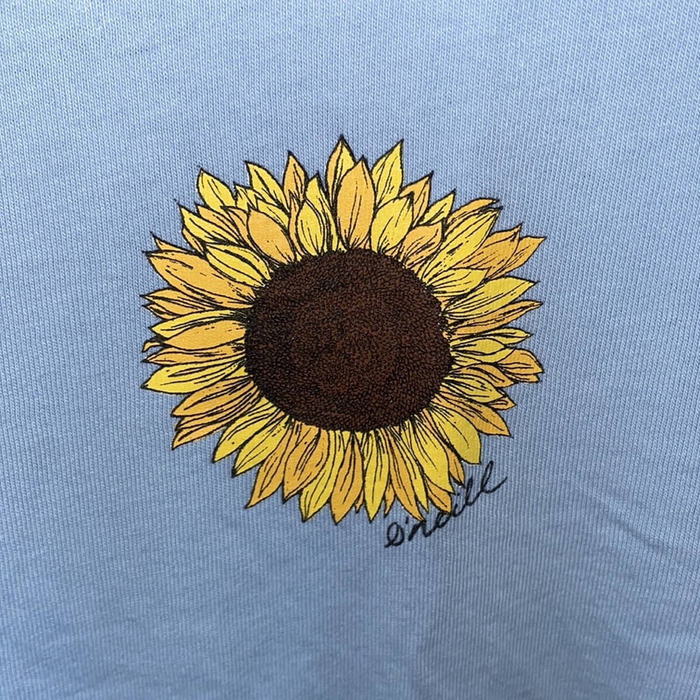O’neill baby blue graphic tee with a sunflower design at the top right